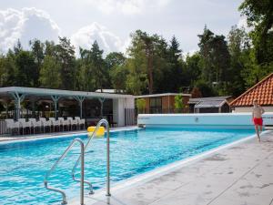 Lovely chalet with covered terrace in a holiday park on the edge of the forest tesisinde veya buraya yakın yüzme havuzu