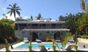 a villa with a swimming pool and palm trees at Petit Havre Bleu in Le Gosier