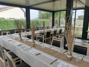 a long table with white tables and chairs in a room at Hotel Martinez Grenay in Grenay