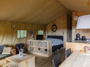 1 dormitorio en una tienda de campaña con 1 cama y 1 mesa en Atmospheric tent lodge with dishwasher in Twente, en Buurse