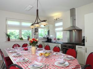 a dining room table with red chairs and a kitchen at Spacious farmhouse in Achterhoek with play loft in Neede