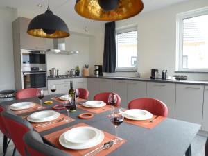 a dining room table with red chairs and a kitchen at Beautiful villa within National Park in Westermient