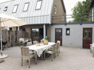 カラントスウオーフにあるBright Holiday Home in Callantsoog with Gardenの建物の前のパティオ(テーブル、椅子付)