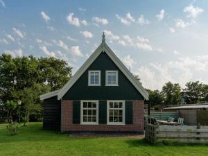 Holiday home on former island Wieringen في Oosterklief: منزل صغير مع سقف أخضر على ساحة