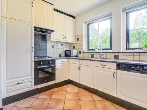 een keuken met witte kasten en een wastafel bij Lovely Holiday Home in Lunteren near Forest in Lunteren