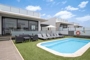 una casa con piscina e sedie e un edificio di Seven Dreams Villas a Corralejo