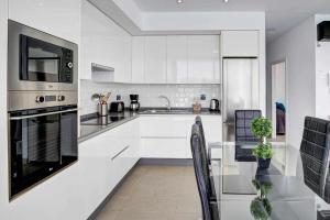 a white kitchen with a sink and a microwave at Seven Dreams Villas in Corralejo