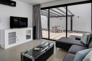 sala de estar con sofá y TV en Seven Dreams Villas, en Corralejo