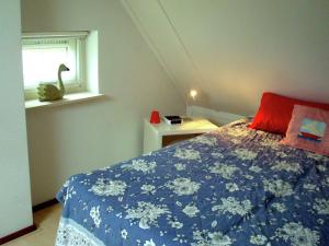 a bedroom with a bed with a blue blanket and a window at Attractive holiday home with jetty in Steendam