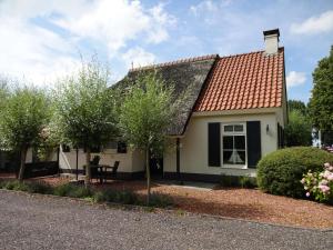 une petite maison blanche avec un toit rouge dans l'établissement Attractive holiday home with jetty, à Steendam