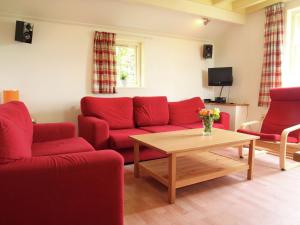 a living room with red couches and a coffee table at Holiday home in quiet surroundings in Sintjohannesga