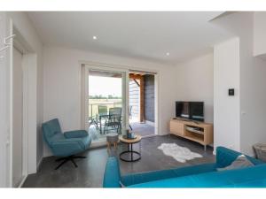 ein Wohnzimmer mit einem blauen Sofa und einem TV in der Unterkunft Wonderfully quiet location in the polder pets allowed close to the beach in Koudekerke