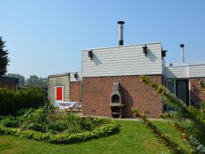 een bakstenen gebouw met een rode deur in een tuin bij Holiday near beach on the Dutch coast in Noordwijkerhout