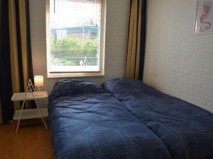 een bed met blauwe lakens in een kamer met een raam bij Holiday near beach on the Dutch coast in Noordwijkerhout