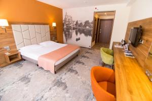 ein Hotelzimmer mit einem Bett, einem Schreibtisch und einem TV in der Unterkunft Kaiserhof Hotel in Kaliningrad