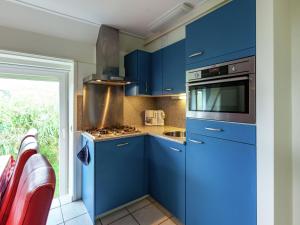 uma cozinha com armários azuis e um forno com placa de fogão em Superb holiday home near the Lauwersmeer em Oostmahorn