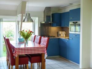 uma cozinha com armários azuis e uma mesa com cadeiras vermelhas em Superb holiday home near the Lauwersmeer em Oostmahorn