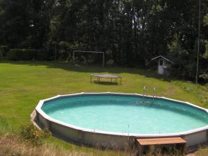 a large swimming pool with a table in a field at lovely house located in a private natural area in Vessem