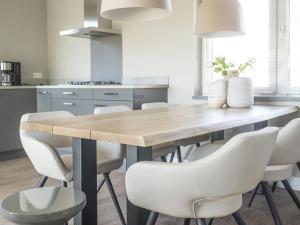 a kitchen with a wooden table and white chairs at Villa in De Cocksdorp with stunning views in De Cocksdorp