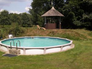 a swimming pool in a field with a gazebo at lovely house located in a private natural area in Vessem