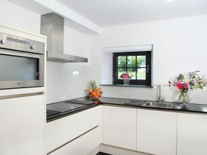 a white kitchen with white cabinets and a sink at Elegant Holiday Home in Epen with Fenced Garden in Epen