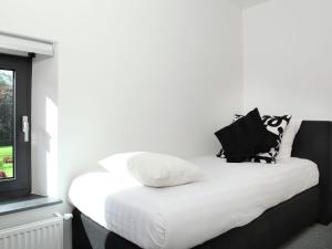 a white bed with black and white pillows on it at Elegant Holiday Home in Epen with Fenced Garden in Epen