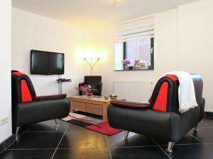 a living room with two chairs and a tv at Elegant Holiday Home in Epen with Fenced Garden in Epen