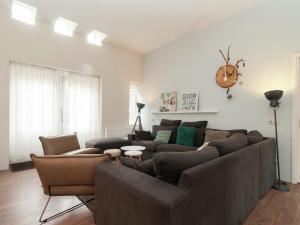ein Wohnzimmer mit einem großen braunen Sofa und Stühlen in der Unterkunft Holiday Home in Bergen aan zee with Terrace in Bergen aan Zee
