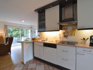 a kitchen with white cabinets and a sink at Attractive bungalow with sauna and hot tub in Voorthuizen