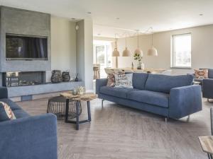 a living room with two blue couches and a fireplace at Lush Villa in De Cocksdorp Texel with Steambath in De Cocksdorp