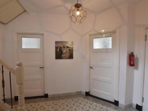 a hallway with two white doors and a picture of a dog at Spacious Farmhouse in IJzendijke with Garden in Schoondijke