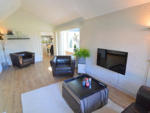 sala de estar con muebles de cuero y TV de pantalla plana en Modern Holiday Home in Haaksbergen with Garden, en Haaksbergen