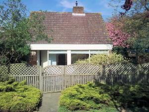 ノールトウェイケルハウトにあるCosy Holiday Home in Noordwijkerhout near Lakeの塀と茂みのある白い家