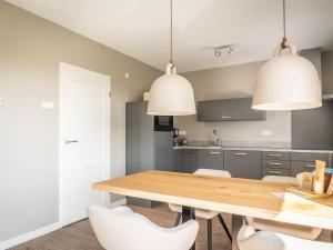 a kitchen with a wooden table and white chairs at fantastic bungalow on Texel in De Cocksdorp