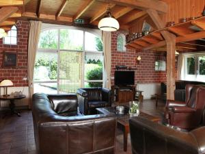 a living room with leather furniture and a large window at Detached farmhouse with play loft in Neede
