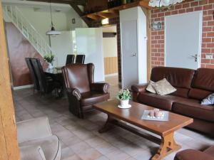 a living room with leather furniture and a table at Detached farmhouse with play loft in Neede