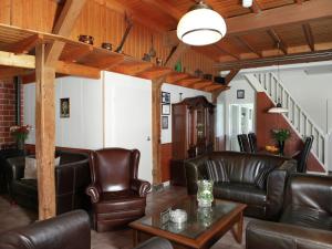una sala de estar con muebles de cuero y techos de madera. en Detached farmhouse with play loft en Neede