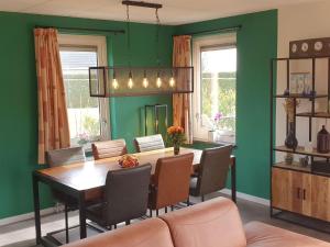 uma sala de jantar com paredes verdes e uma mesa e cadeiras em Nice holiday home with sauna and jacuzzi near the Wadden Sea em Tzummarum
