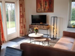 a living room with a couch and a tv and a table at Nice holiday home with sauna and jacuzzi near the Wadden Sea in Tzummarum