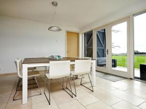 a dining room with a table and white chairs at Modern large villa on the mudflats in Friesland in Wierum