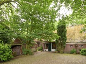 una casa de ladrillo con un árbol delante de ella en Quietly located farmhouse with sauna and hot tub, en Balkbrug