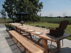 een lange houten tafel met stoelen en een parasol bij Countryside Villa in Zuidzande with Private Garden in Zuidzande