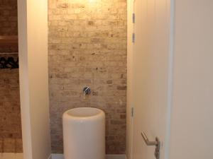 een toilet in een badkamer met een bakstenen muur bij Countryside Villa in Zuidzande with Private Garden in Zuidzande