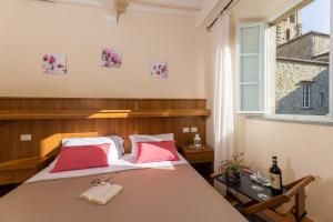 Schlafzimmer mit einem Bett mit roten Kissen und einem Fenster in der Unterkunft B&B San Francesco in Cortona