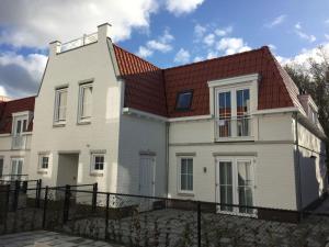 a white house with a red roof at Luxury apartment for 6 people with roof terrace and view of the dunes in Koudekerke