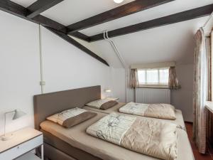 2 camas num quarto com paredes brancas e vigas de madeira em Cozy Holiday Home in Oisterwijk with Swimming Pool em Oisterwijk