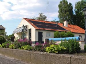 een wit huis met een oranje dak en een aantal planten bij Cozy Holiday Home in Oisterwijk with Swimming Pool in Oisterwijk