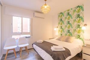 a bedroom with a bed and two white chairs at Faro, bonito apartamento en la Malagueta in Málaga