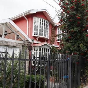 une maison rouge avec une clôture et un arbre dans l'établissement Hospedaje familiar Gloria, à Punta Arenas