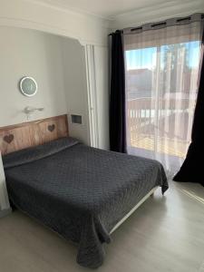 a bedroom with a bed and a window with a balcony at Hôtel le Canetois in Canet-en-Roussillon